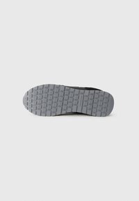 Schuhsohle aus strukturiertem grauem Gummi, mit rechteckigen Mustern und kreisförmigen Details für besseren Halt. Schwarze Kanten sorgen für Langlebigkeit.
