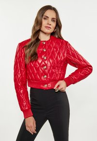 Gequilted rode leren jas met gouden knopen, geribbelde manchetten en een cropped ontwerp, gecombineerd met zwarte strak zittende broeken. Glad textuur overal.