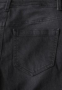 Zwarte denim jeans met een enkele achterzak met een puntige klep. Gladde textuur met zichtbare stikdetails.