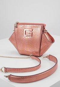 Käsilaukku ruusukullassa, jossa on teksturoitu käärmeennahkakuosi. Varustettu GG-logo-lukolla, ketjuhihnalla ja rakenteellisella siluetilla.