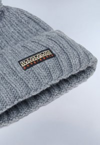 Beanie grigio lavorato a maglia con un motivo a coste e un risvolto. Presenta un'etichetta nera rettangolare con "Napapijri" in lettere beige e arancioni.