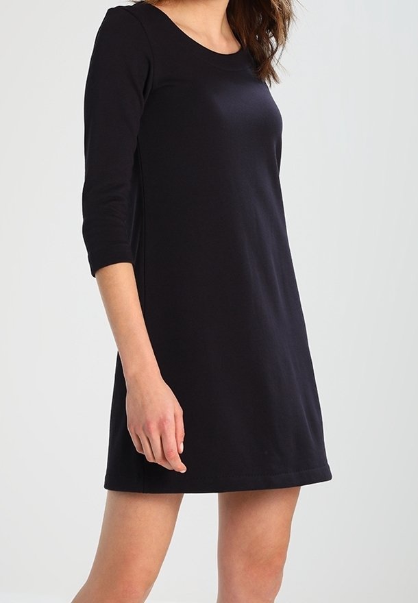 Vestido negro ajustado con mangas de tres cuartos, escote redondo y una textura suave. Longitud a la rodilla sin patrones ni adornos visibles.