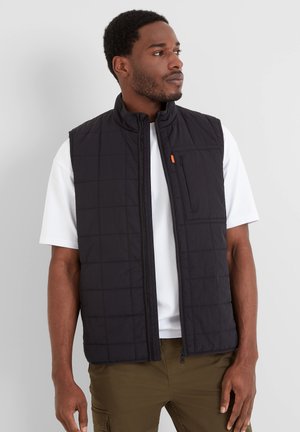 Black quilted vest with a stand-up collar, featuring a zip pocket and a full front zipper, worn over a white T-shirt.
