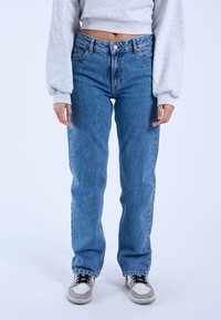 Light blue denim jeans with a high waist, straight-leg fit, slightly distressed texture, and five-pocket design. Paired with gray sneakers.
