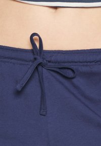 Cintura elástica de algodón azul marino con un detalle de lazo. Textura suave y diseño elástico para un ajuste cómodo.