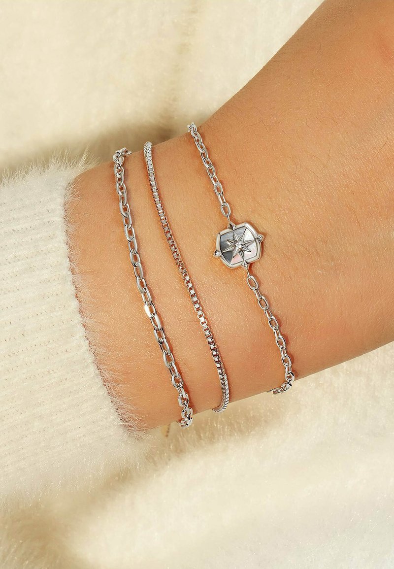 Trio di bracciali in argento composto da una catena liscia, una catena con maglie testurizzate e una con un pendente ottagonale caratterizzato da un design a stella.