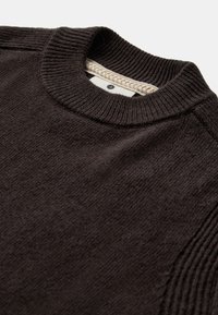 Maglione marrone scuro con scollo tondo a coste, tessuto testurizzato e etichetta di colore chiaro a contrasto con dettaglio intrecciato.