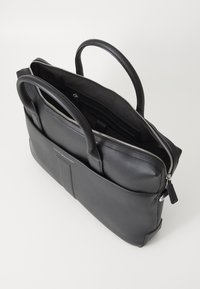 Black leather bag with a smooth texture, dual handles, and a silver zipper. Features an interior compartment and a front pocket.
