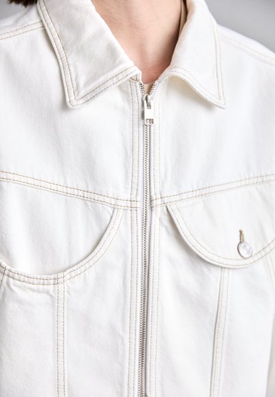 Weißer Jeansjacke mit einem Frontreißverschluss und zwei Brusttaschen. Verfügt über kontrastierende beigefarbene Nähte und ein klassisches Hemdkragen-Design.