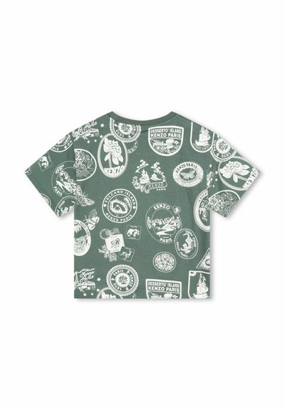 T-shirt en coton vert avec des écussons graphiques blancs présentant divers motifs, y compris des motifs floraux et scéniques, formes rondes et rectangulaires.