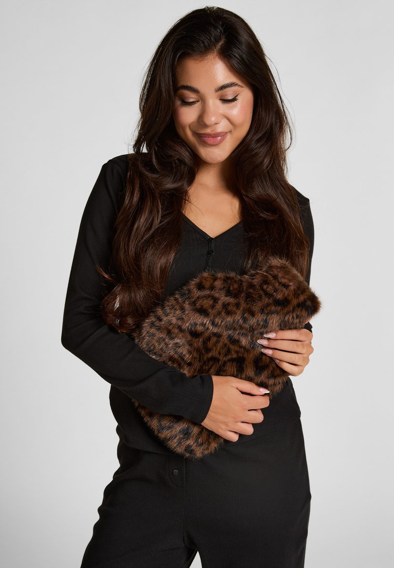 Brown leopard-print fur clutch held against a black long-sleeve top. Features soft texture and rounded shape with a rich, patterned surface.