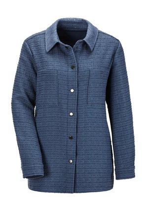 Donkerblauwe geweven jas met een kraag, knoopsluiting, twee borstzakken en gestructureerde stof. Kenmerkend zijn de zichtbare stiksels en metalen knopen.