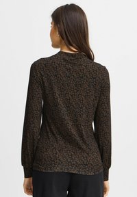 Juodas ilgomis rankovėmis marškinėliai su rudu lapų raštu, minkšta medžiaga, apvaliu kaklu ir pritaikyta konstrukcija, su šiek tiek lenktu apačiu.