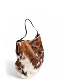Borsa a tracolla in pelle di mucca con un motivo a patchwork marrone e bianco, texture morbida e una singola tracolla in pelle.