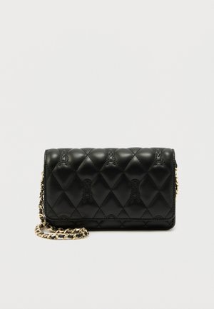 Sac bandoulière en cuir noir matelassé avec chaîne dorée et motif de logo embossé subtil sur fond uni.