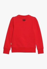 Sudadera roja de manga larga, con puños y dobladillo acanalados. Presenta un pequeño texto bordado en negro en la parte posterior. Material suave, corte casual.