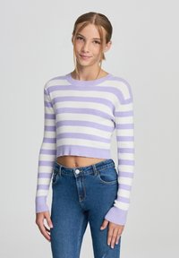 Maglione cropped a righe viola e bianche con texture a costine e maniche lunghe, abbinato a jeans denim blu con vestibilità classica e tasche.