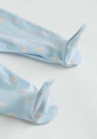 Pyjama bébé bleu clair avec pieds, imprimé de marguerites blanches et jaunes, doté d'un tissu doux et de manches avec poignets à retourner en forme de moufles.