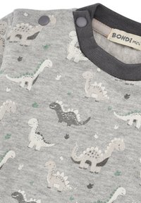 Grauer Baumwollpullover mit Dinosaurierdruck in Weiß, Grün und Schwarz. Verfügt über Druckknöpfe an der Schulter und einen gerippten Ausschnitt.