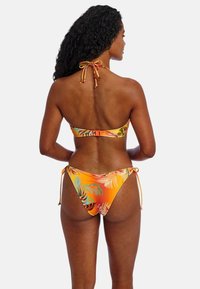 Bikini multicolor con un patrón floral tropical. La parte superior tiene un diseño de cuello halter, y la parte inferior se ata a los lados con cuerdas ajustables.