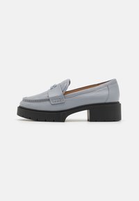 Mocassins en cuir gris clair avec une tige texturée, des détails cousus et un talon plateforme noir épais. Design élégant et ajusté.