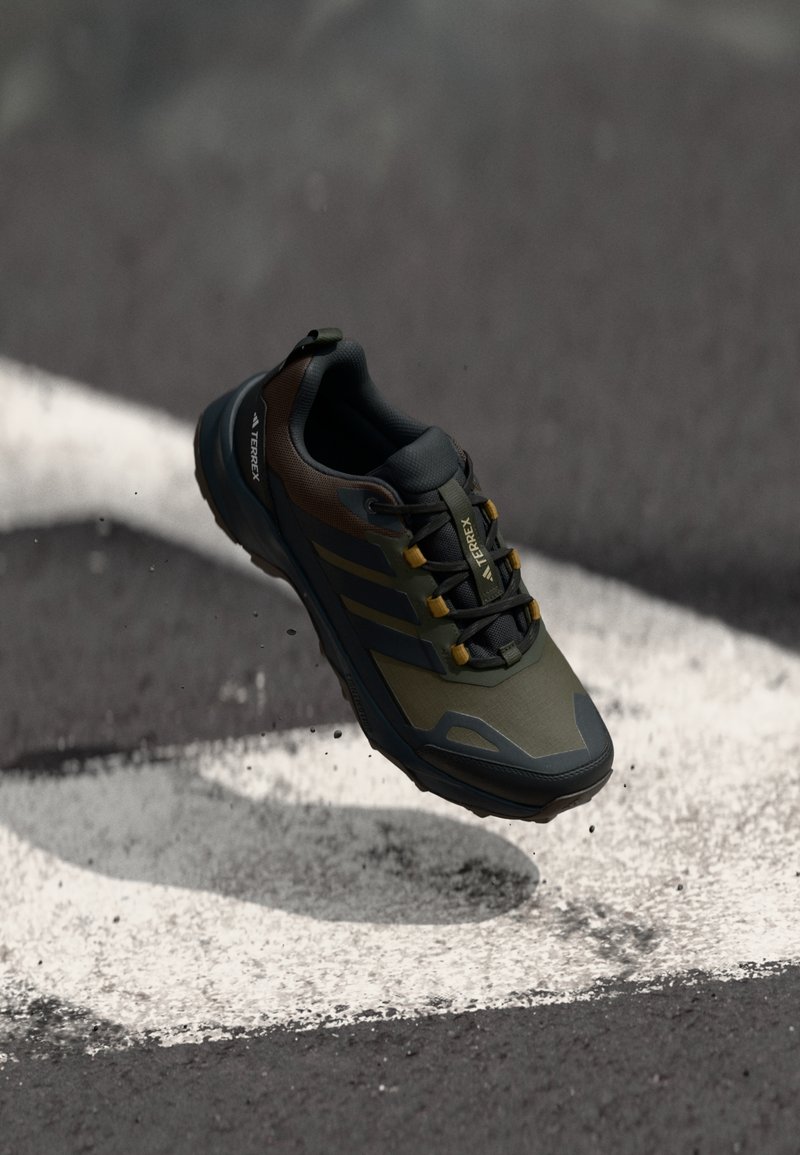 Scarpa outdoor Terrex in verde scuro e marrone, con tomaia testurizzata, suola in gomma e sistema di allacciatura integrato per una vestibilità sicura.