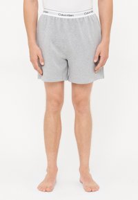 Graue Baumwoll-Boxer mit elastischem Bund, der das Logo "Calvin Klein" trägt. Einfaches Design, gerader Schnitt und weiche Textur.