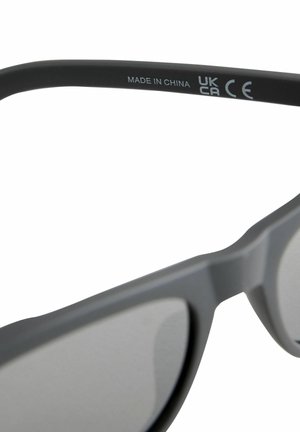 Šedé sluneční brýle s matným povrchem, které mají minimalistický design a zabarvené čočky. Na brýlích jsou označení "Vyrobeno v Číně", UKCA a certifikace CE.