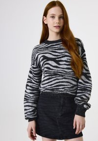 Zwart-wit gestreepte trui met een ronde halslijn en een losse pasvorm, gecombineerd met een zwarte denim rok met een subtiele textuur.