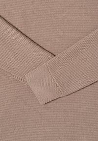 Jasnoróżowa tkanina o fakturze z prążkowanym wzorem. Mankiety mają gładkie wykończenie, które uzupełnia ogólny design.