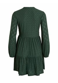 Mörkgrön klänning med långa ärmar, i ett texturerat tyg med utskurna mönster, en flerdelad kjol och rund halsringning.