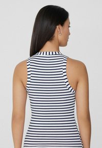 Top sin mangas de canalé con rayas horizontales en azul marino y blanco, diseño ajustado, cuello alto y textura suave.