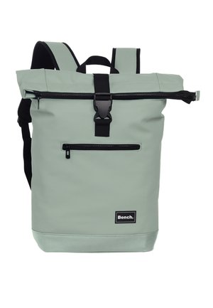 Sac à dos vert clair à rabat roulé avec une fermeture éclair noire, une poche avant et un écusson du logo Bench au centre du bas.