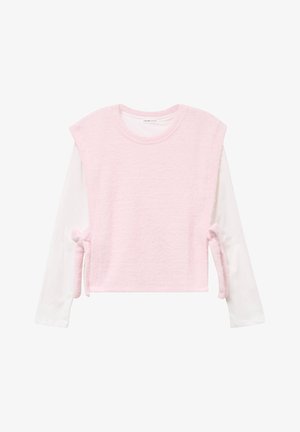 Roze gebreide sweater met korte mouwen, gedragen over een wit shirt met lange mouwen. Heeft strikjes aan de zijkanten voor aanpassing.