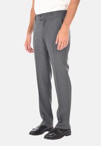 Pantaloni grigi su misura con una vestibilità dritta, caratterizzati da una superficie liscia e una chiusura con bottone. Abbinati a scarpe formali nere.