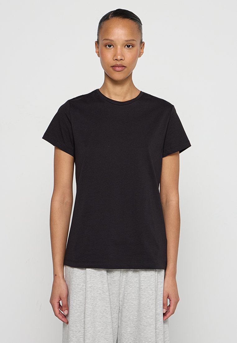 Camiseta de algodón negra, con cuello redondo, mangas cortas, corte recto. Textura suave, diseño simple sin patrones ni acentos.