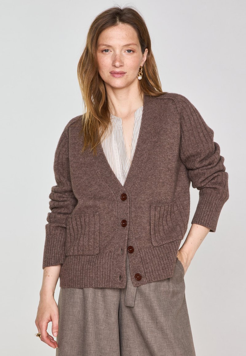 Cardigan en laine marron avec des manches côtelées et deux poches avant, doté de boutons marron foncé et d'un décolleté en V profond.