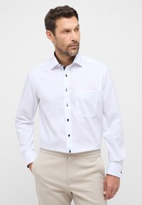 Witte overhemd met lange mouwen, een button-down kraag, marineblauwe knopen, een enkel borstzakje en contrasterende manchetten, gemaakt van soepel materiaal.