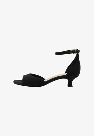 Black open-toe sandal featuring a curved design, soft material, a thin ankle strap with a gold buckle, and a low heel.