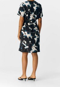 Kurzärmliges Kleid mit schwarzem Grundton und abstrakten blauen und weißen Blumenmustern, lockerer Passform und gebundenem Taillengurt.