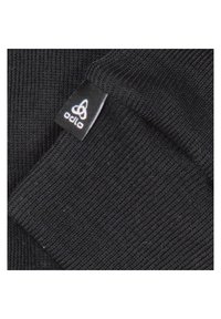Tissu tricoté noir avec une texture côtelée. Présente une petite étiquette de marque noire et blanche avec un logo sur le bord.