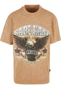 Brun vintage T-shirt med et grafisk tryk af en ørn og teksten "KARL KANI EST. 1989". Blødt, tekstureret stof med en løs pasform.