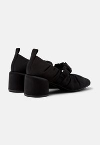 Scarpe con tacco in tessuto nero con tacco spesso, caratterizzate da un design arricciato nella parte superiore e punta affusolata, superficie testurizzata e linguette sul retro.