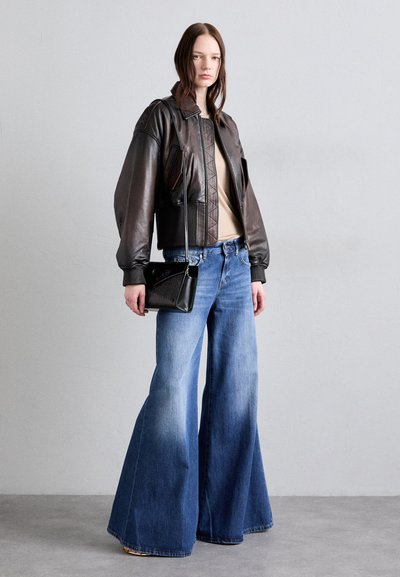 Brun læder bomberjakke med ribbede manchetter, beige top, vide ben blå denim jeans og en lille sort crossbody taske.