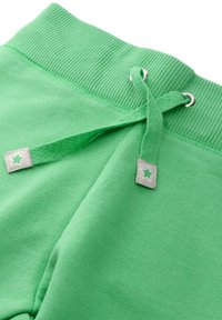 Grüne Jogginghose mit geripptem Bund, Kordelzug mit silbernen Ösen und dekorativen Laschen mit Sternmustern. Aus weichem Baumwollmaterial.