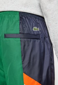 Groene en marineblauwe colorblock shorts met een textured afwerking, voorzien van een geborduurd logo, elastische taille en een zijzak.
