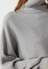 Maglione grigio a collo alto con costine, di vestibilità comoda, caratterizzato da un colletto alto e un tessuto morbido e strutturato.