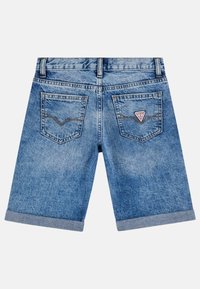 Shorts en denim de couleur bleu clair avec un ourlet retroussé, deux poches arrière arborant un patch logo en triangle, et des détails de couture visibles.