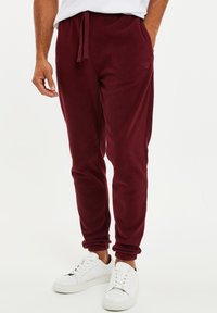 Bordeaux fleece joggers met een elastische tailleband en boorden, voorzien van zijzakken en een subtiele logodetail op de dij.