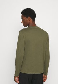 Langermet olivengrønn skjorte laget av bomull, med rund hals og et enkelt design, sett fra baksiden.